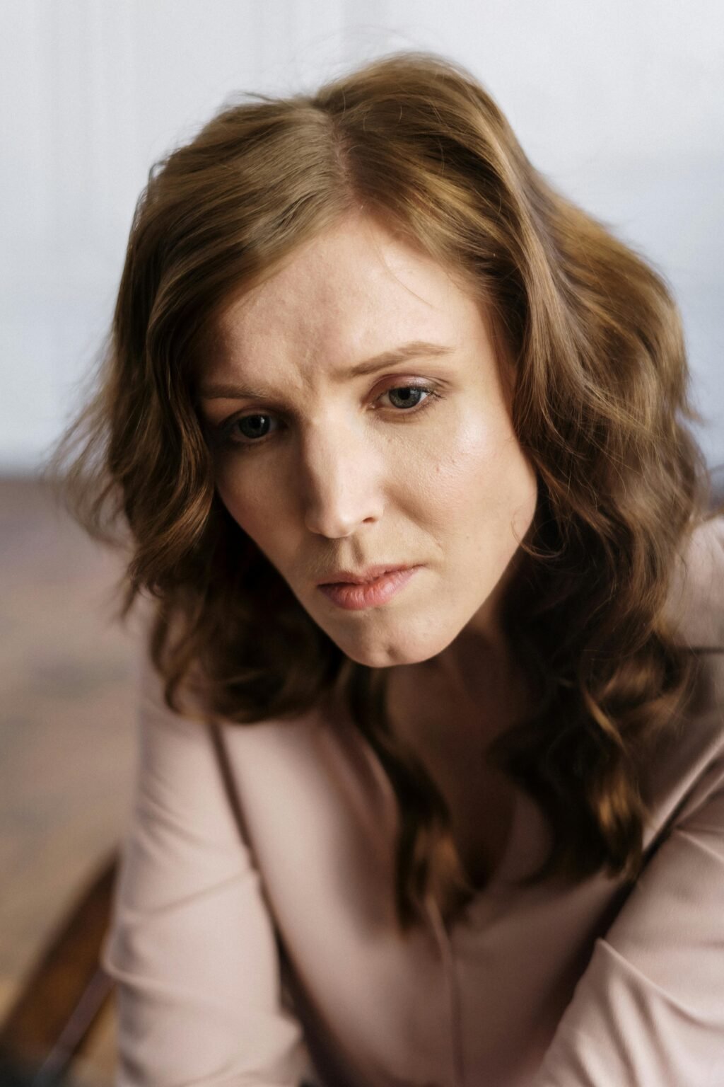 A woman with curly hair in deep thought, indoors, conveying emotion.