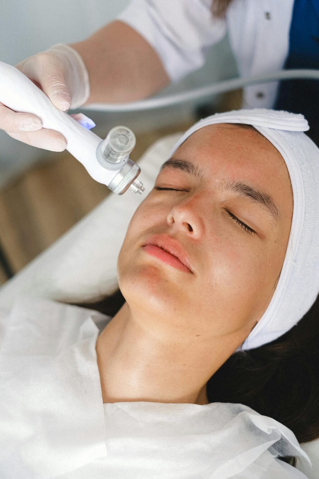 A client receiving a facial skincare treatment at a spa by a professional beautician using advanced equipment.
