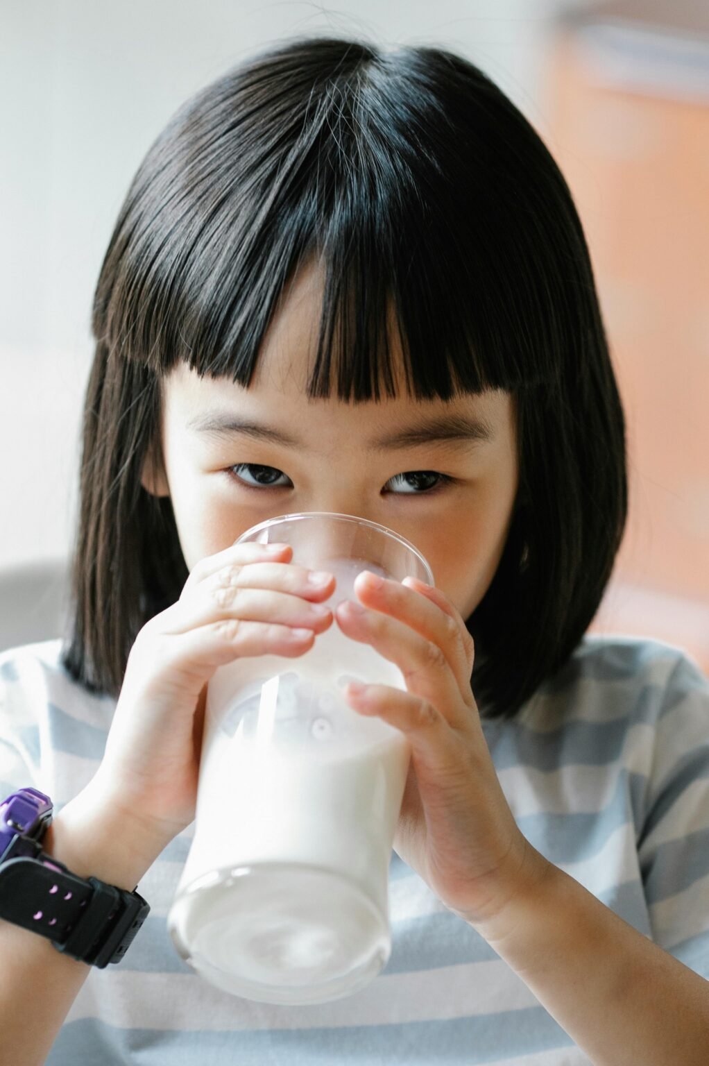 Happy child drinking fresh milk indoors, promoting healthy lifestyle and nutrition.