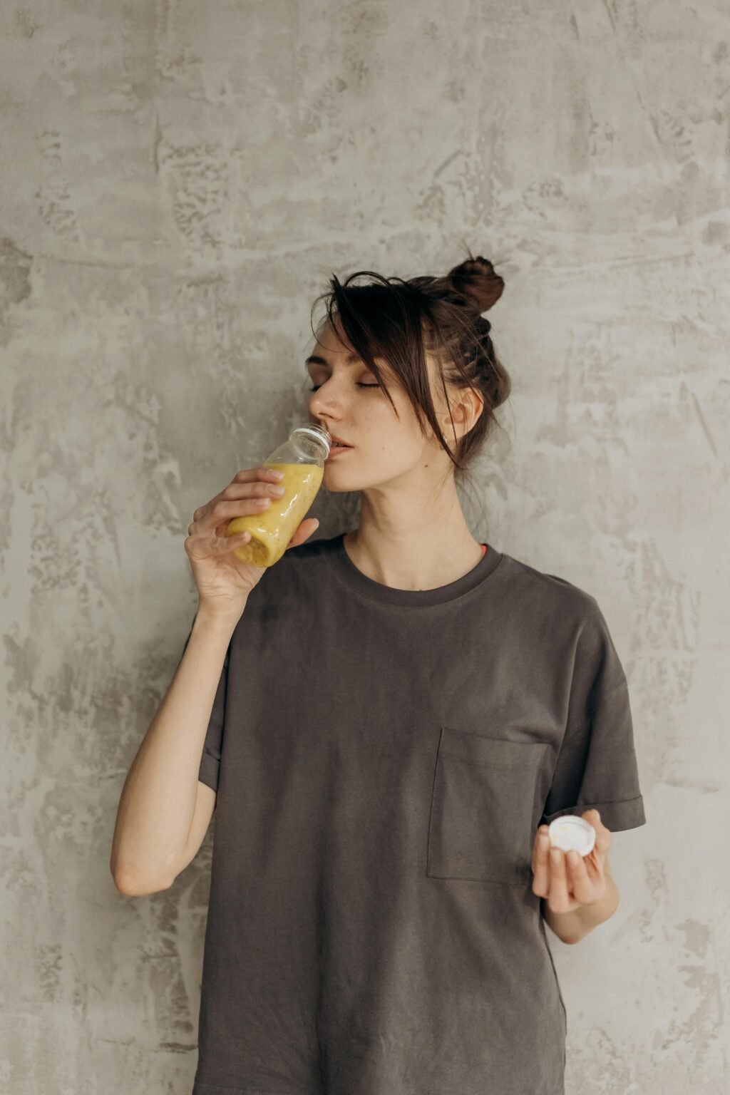 A young woman drinks refreshing juice indoors, embracing a healthy lifestyle.